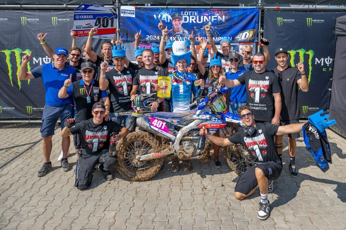 A equipa De Baets AIT Racing Yamaha a festejar junto à moto, com uma faixa de Lotte van Drunen ao fundo